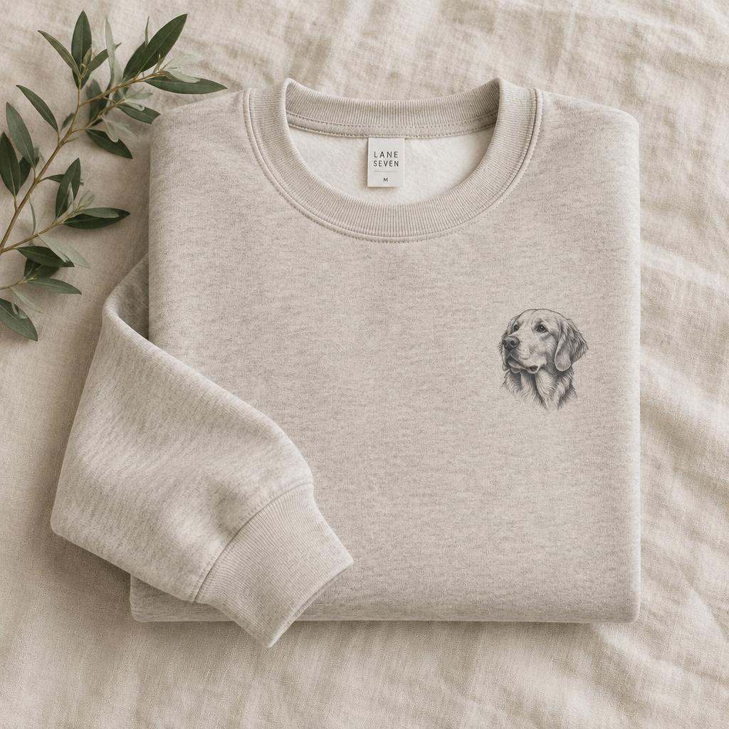 Oatmeal crewneck sweatshirt folded on linen with a custom dog portrait on the chest